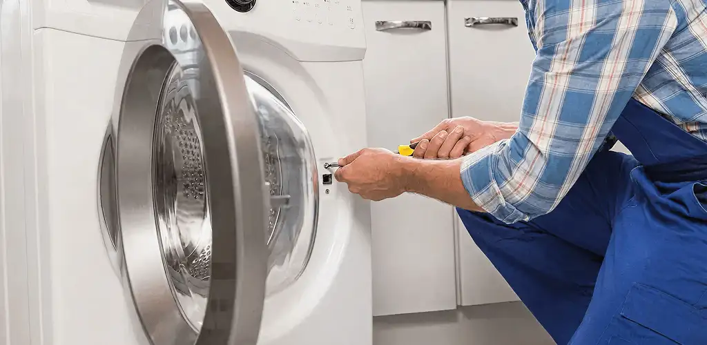 Handyman repairing a clothes dryer and checking electrical connections in Sioux Falls, SD
