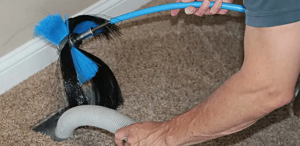Dryer vent cleaning technician brushing lint from a vent line in Sioux Falls, SD