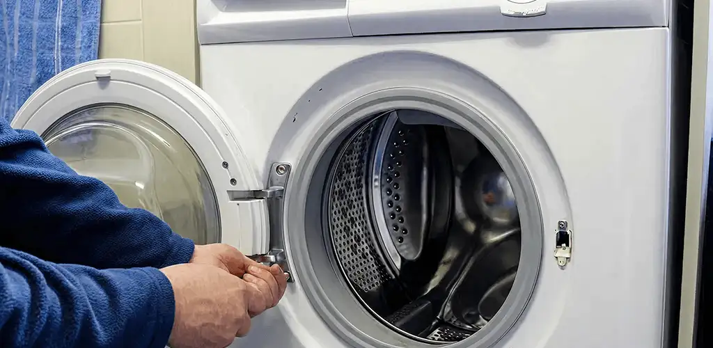 Washing machine repair handyman checking a front-load washer door and latch in Sioux Falls, SD