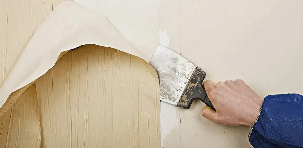 Handyman removing wallpaper with a scraper for wall preparation in Sioux Falls, SD