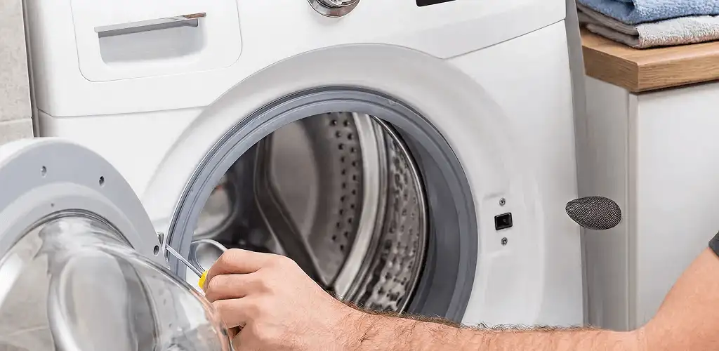Handyman repairing a front-load washing machine and inspecting the drum in Sioux Falls, SD
