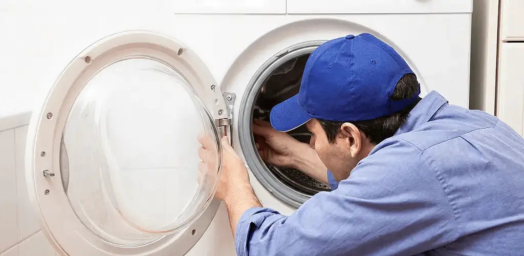 Washing machine repair handyman inspecting a front-load washer drum in Sioux Falls, SD