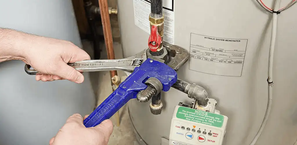 Water heater repair technician tightening the shutoff valve and supply line in Sioux Falls, SD